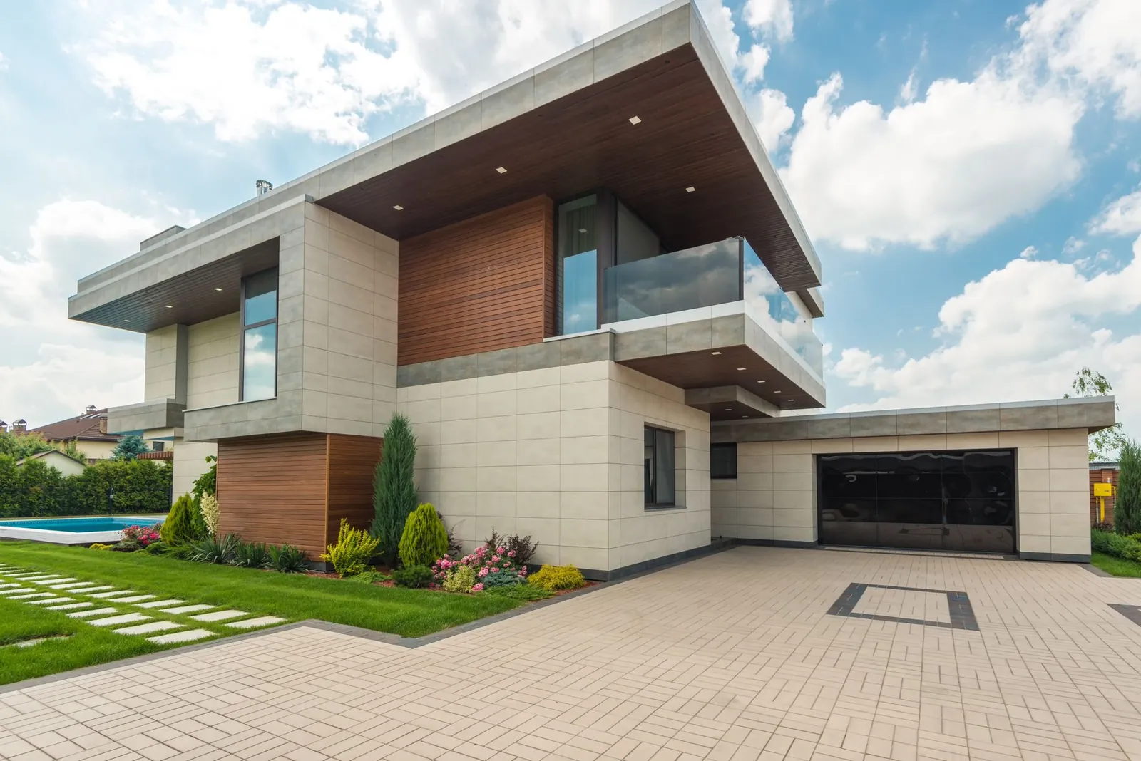 Contemporary luxury house with a sleek design, lush garden, and blue sky. Stock photo illustrating Embassy Developments' fund raise story.