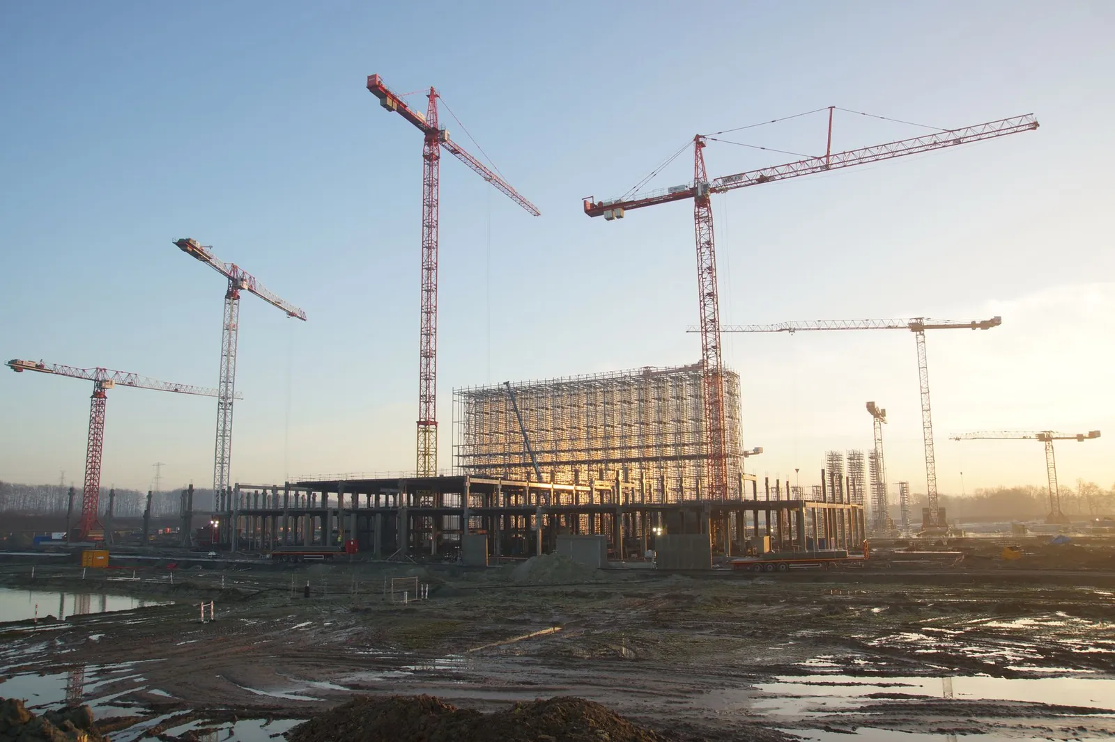 Wide view of a construction site with cranes and building framework at sunset. Industrial landscape. Stock photo illustrating Consolidated Construction Consortium's new order story.