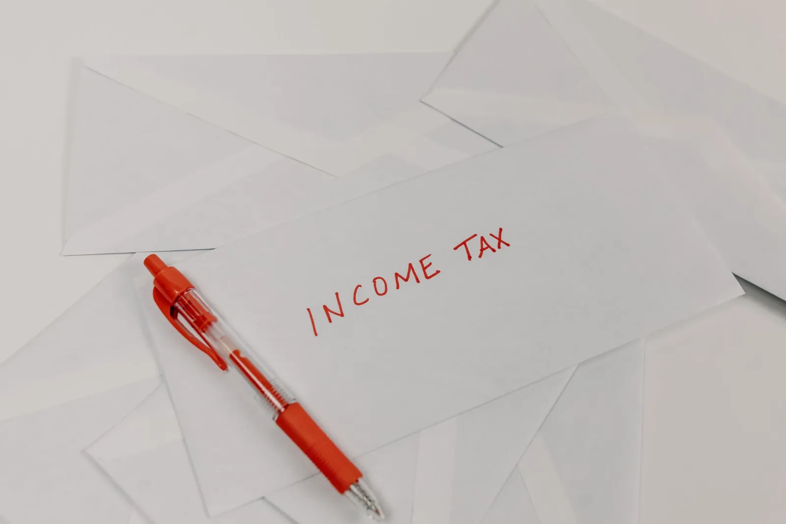 Studio shot of income tax envelope with red pen for accounting and tax season preparation. Stock photo illustrating The Karnataka Bank's product launched story.