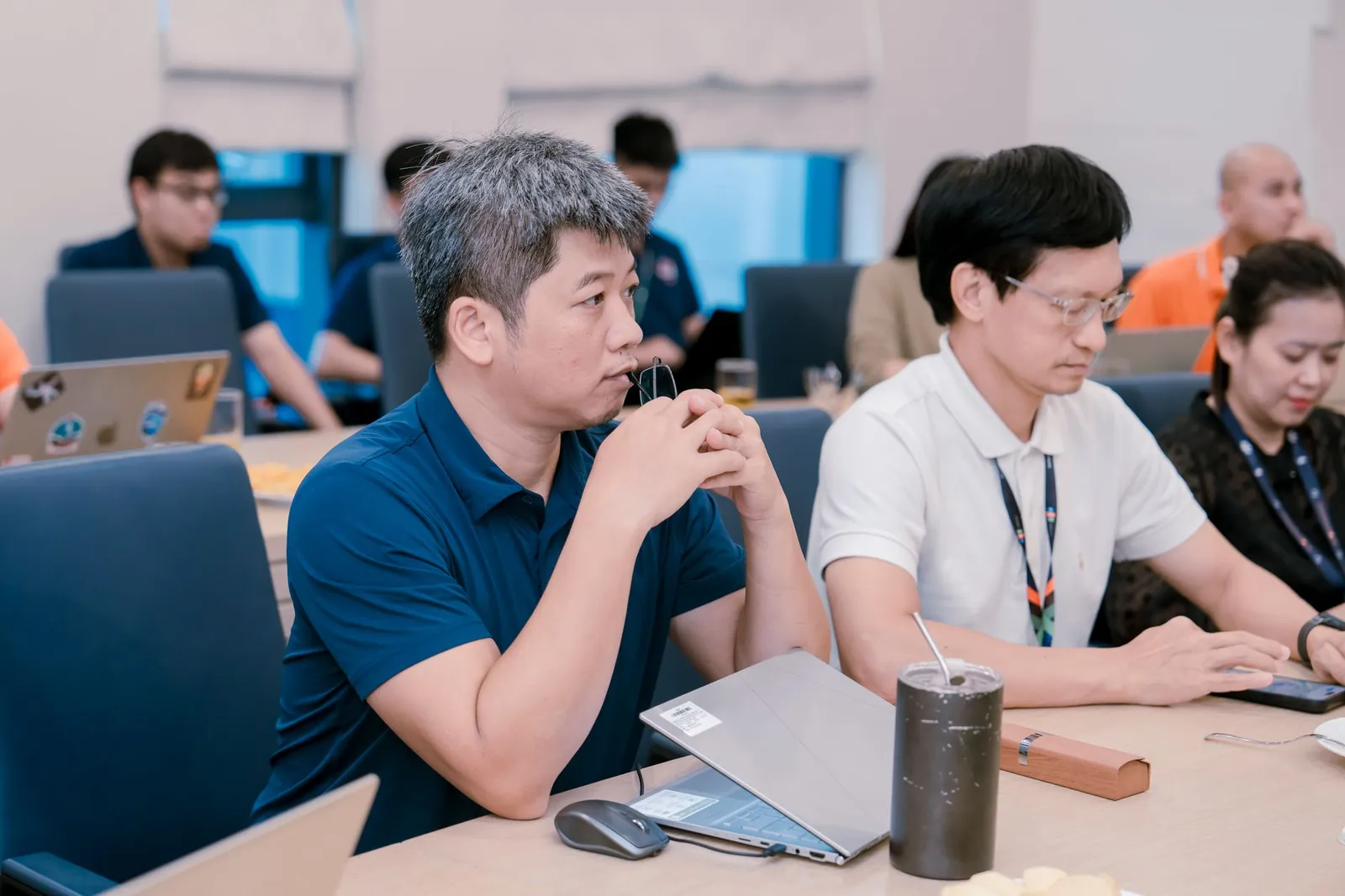Engaged professionals in a corporate meeting room discussing ideas with laptops and notes. Stock photo illustrating NIIT's earning call story.