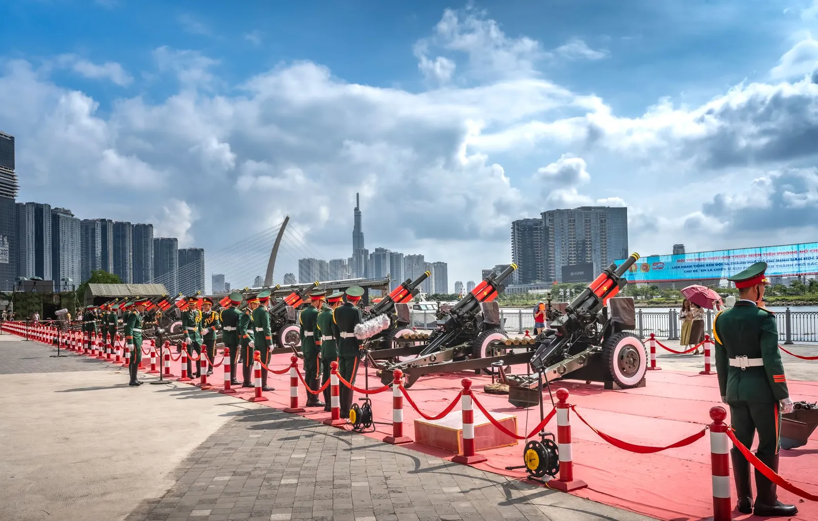Military personnel at a ceremonial event with artillery by the riverside, urban skyline backdrop. Stock photo illustrating Sigma Advanced Systems' new order story.