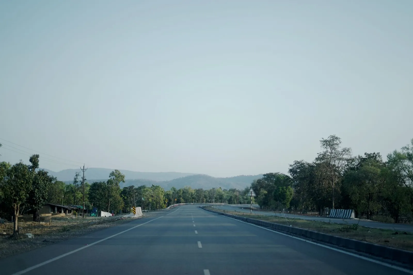 Empty highway through lush countryside of Ambikapur, CG, India under a clear sky. Stock photo illustrating IRB Infrastructure Developers' new order story.