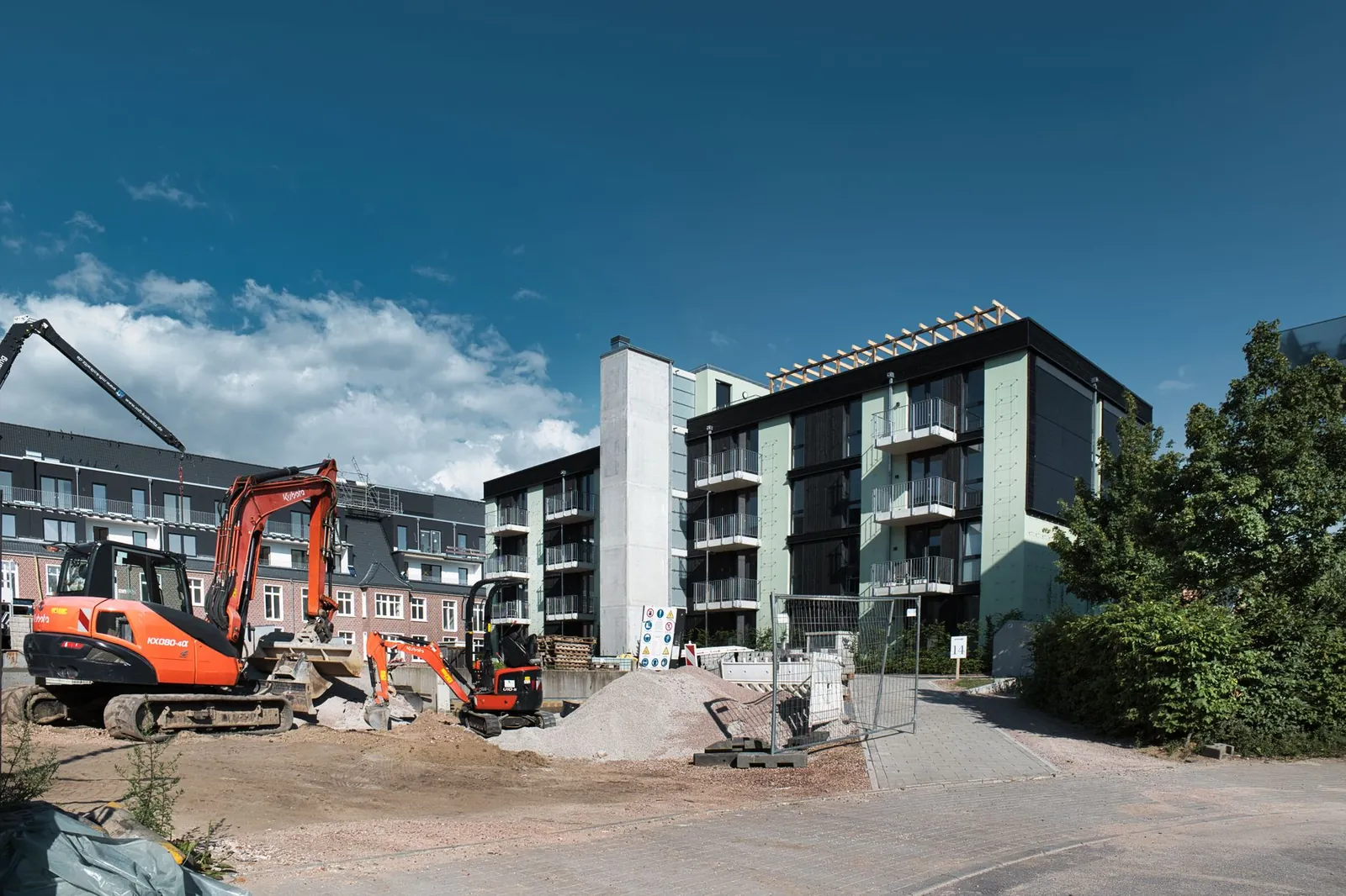 Active construction site with machinery next to modern apartments under blue sky. Stock photo illustrating Veegaland Developers' promoter buying story.