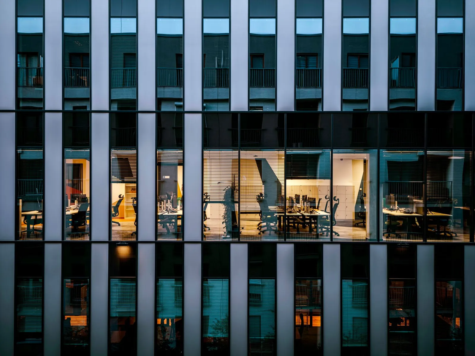 Illuminated office inside a modern glass building exterior, showcasing architecture and workspace design. Stock photo illustrating Interise Trust's fund raise story.