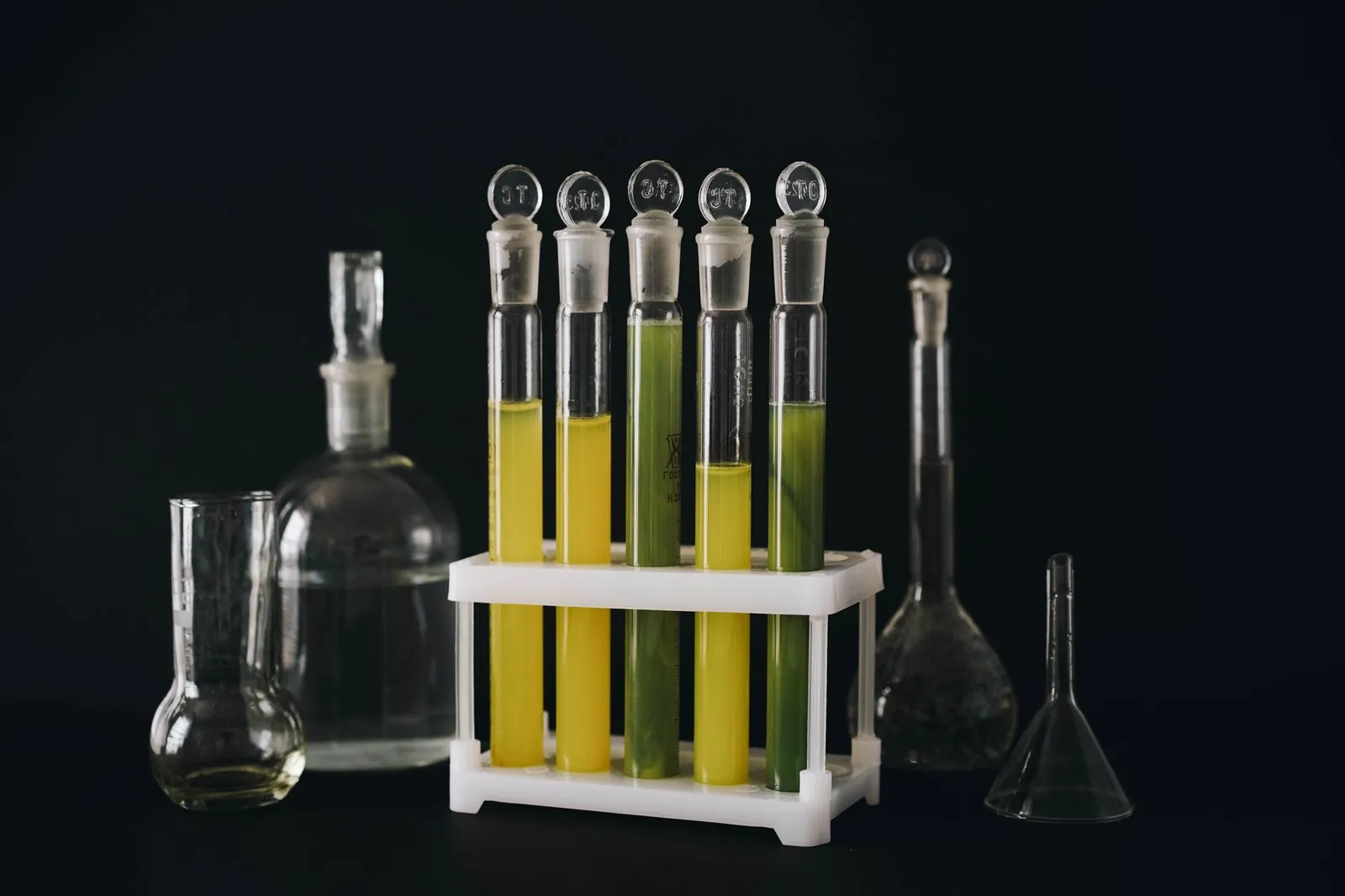 A collection of vibrant liquids in test tubes against a black background, showcasing chemistry equipment. Stock photo illustrating Anupam Rasayan India's product launched story.