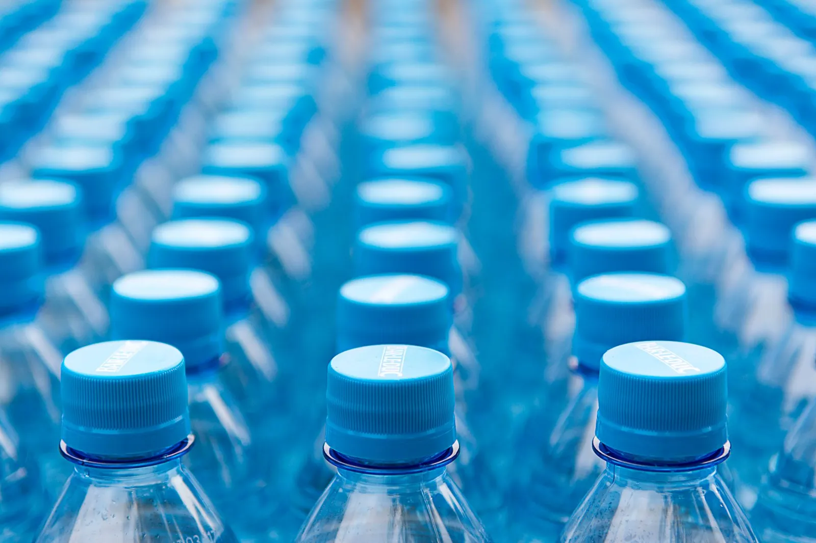 Array of blue plastic water bottles with caps arranged in a pattern. Ideal for recycling and packaging themes. Stock photo illustrating United Breweries' product launched story.