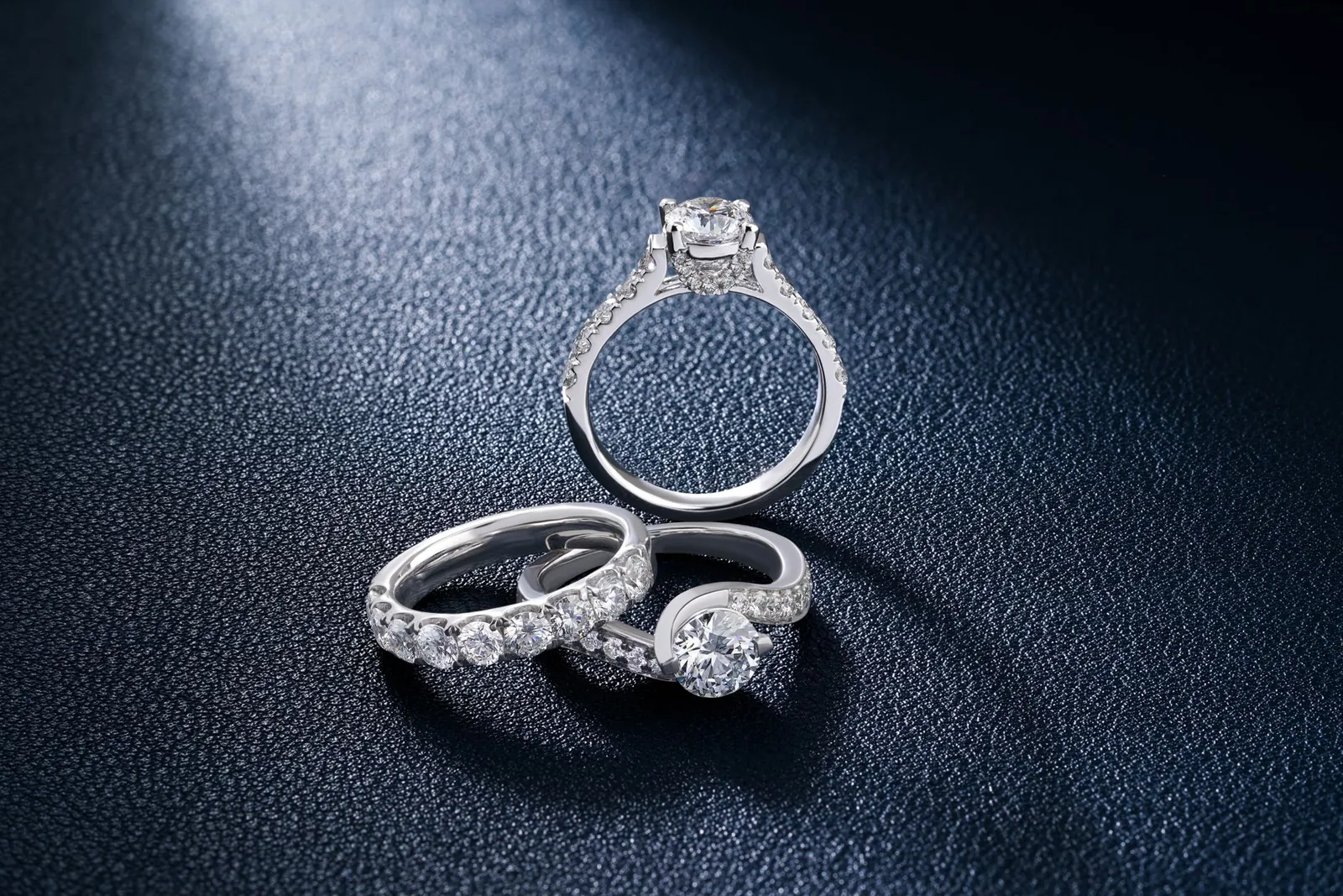 Close-up of luxurious diamond engagement and wedding rings on a textured surface, showcasing elegance and craftsmanship. Stock photo illustrating Mini Diamonds (India)'s product launched story.