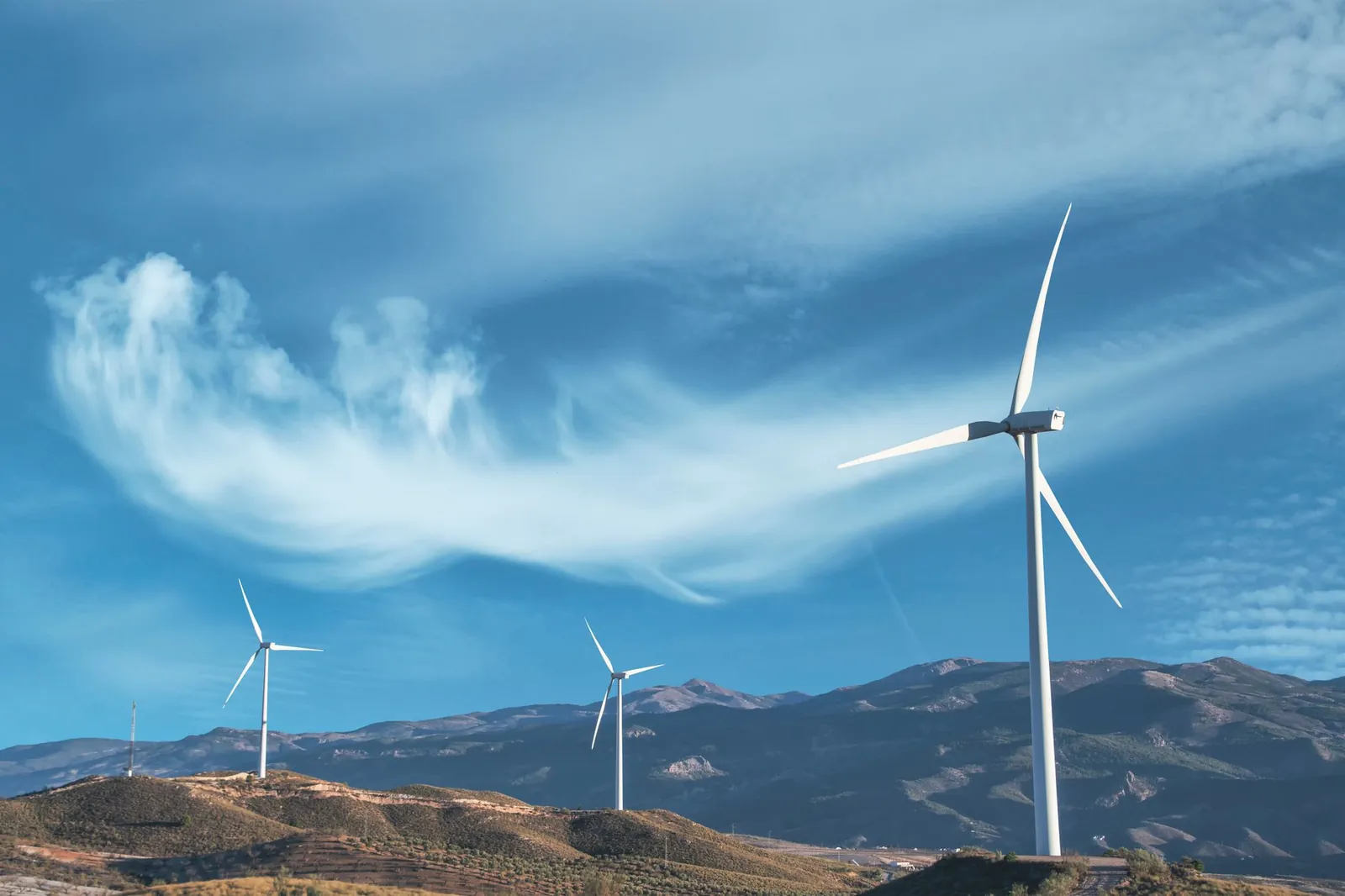 Wind turbines on a hillside capturing clean energy under a serene blue sky. Stock photo illustrating MTAR Technologies' earning call story.