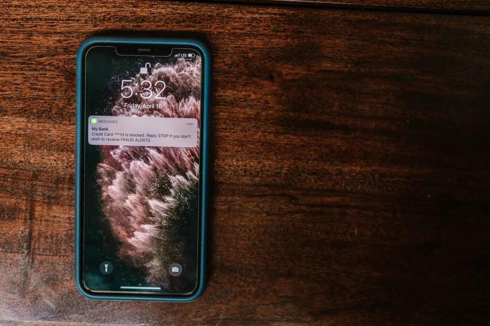 Close-up of smartphone on wooden surface displaying a bank alert message. Stock photo for the ALFA News guide: Watchlist Alerts in India: A Guide for Investors.