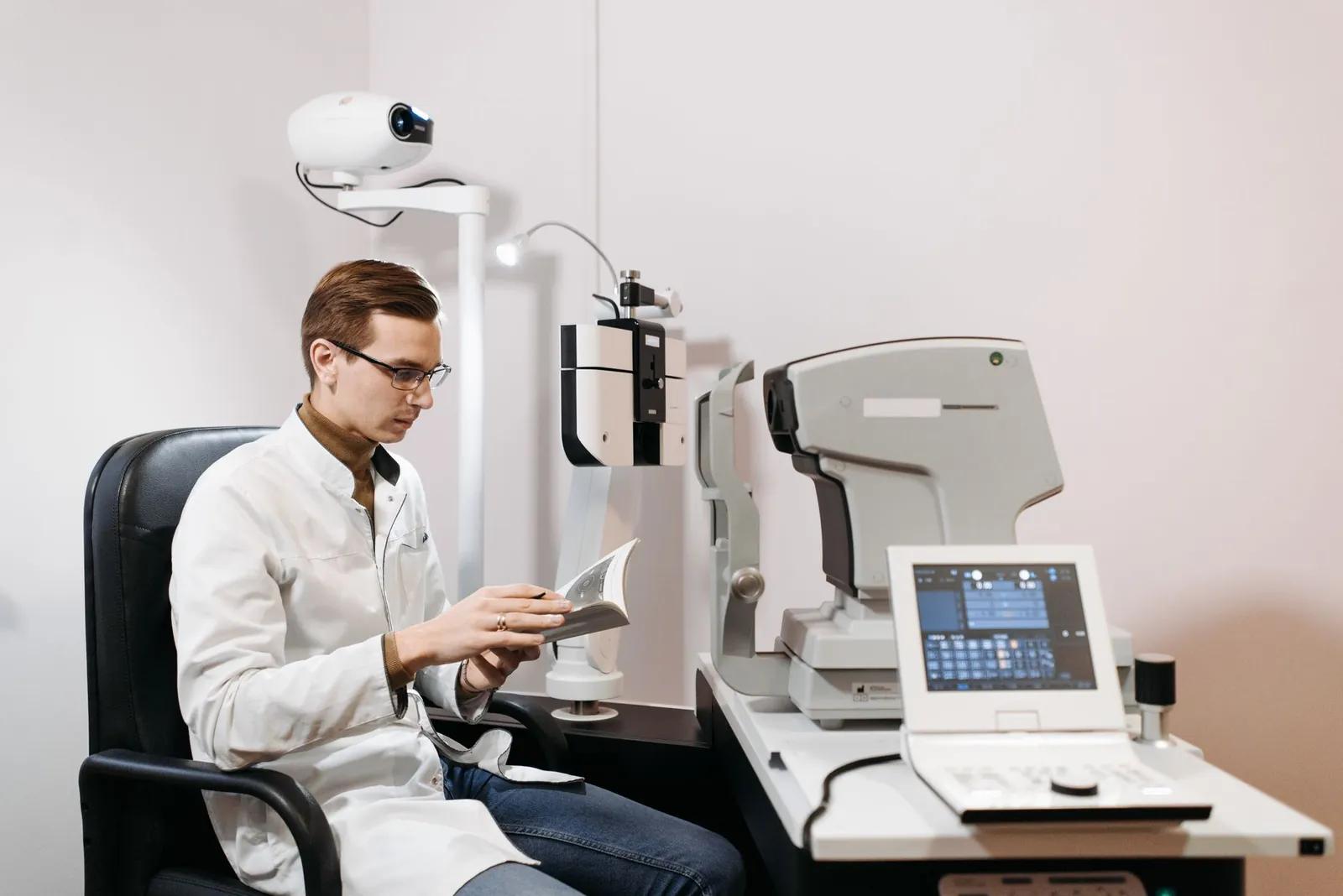 Eye care professional in clinic using ophthalmology equipment, wearing glasses and a lab coat. Stock photo illustrating Novartis India's partnership story.