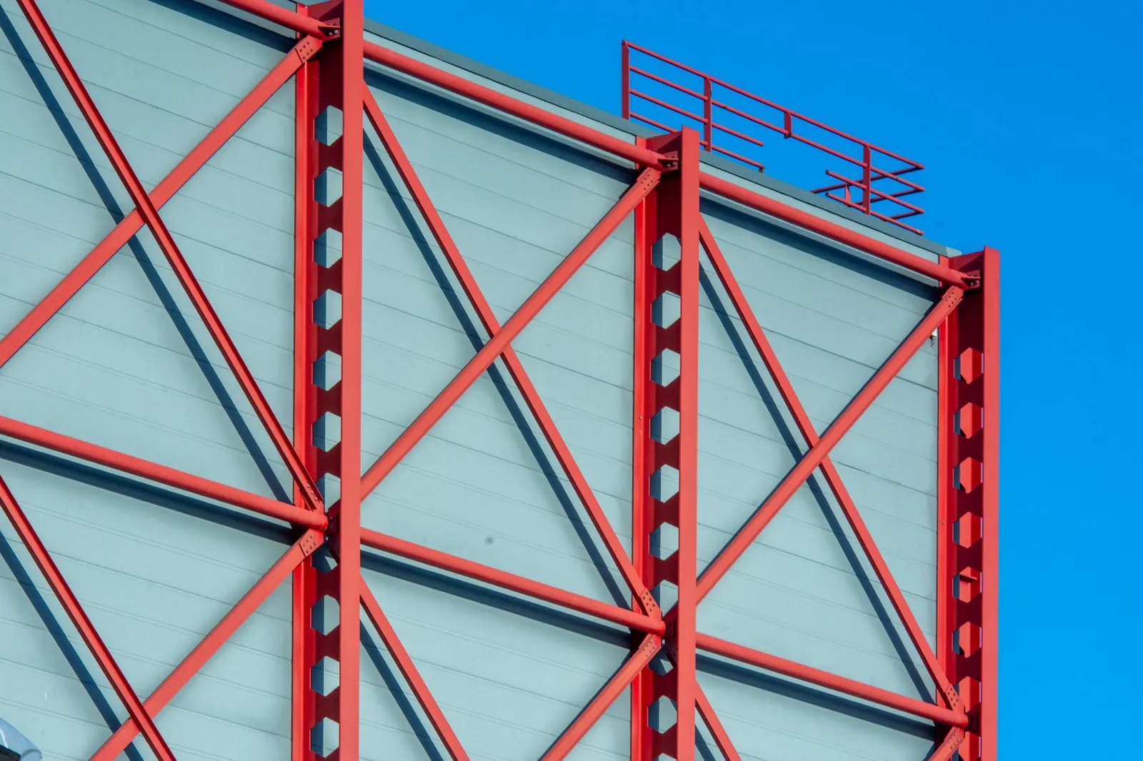 Close-up of a modern building facade featuring red steel beams in geometric patterns against a blue sky. Stock photo illustrating Interarch Building Solutions' earning call story.