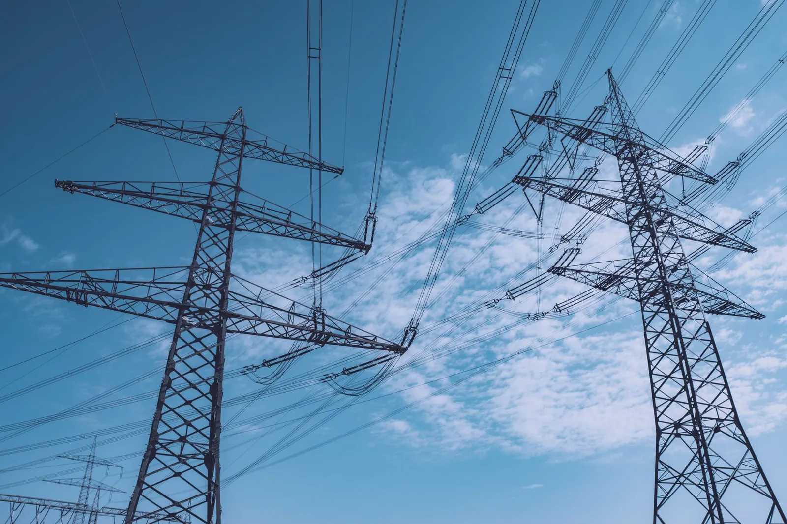High voltage transmission towers stretch across a clear blue sky, symbolizing energy and industry. Stock photo illustrating Bajel Projects' new order story.