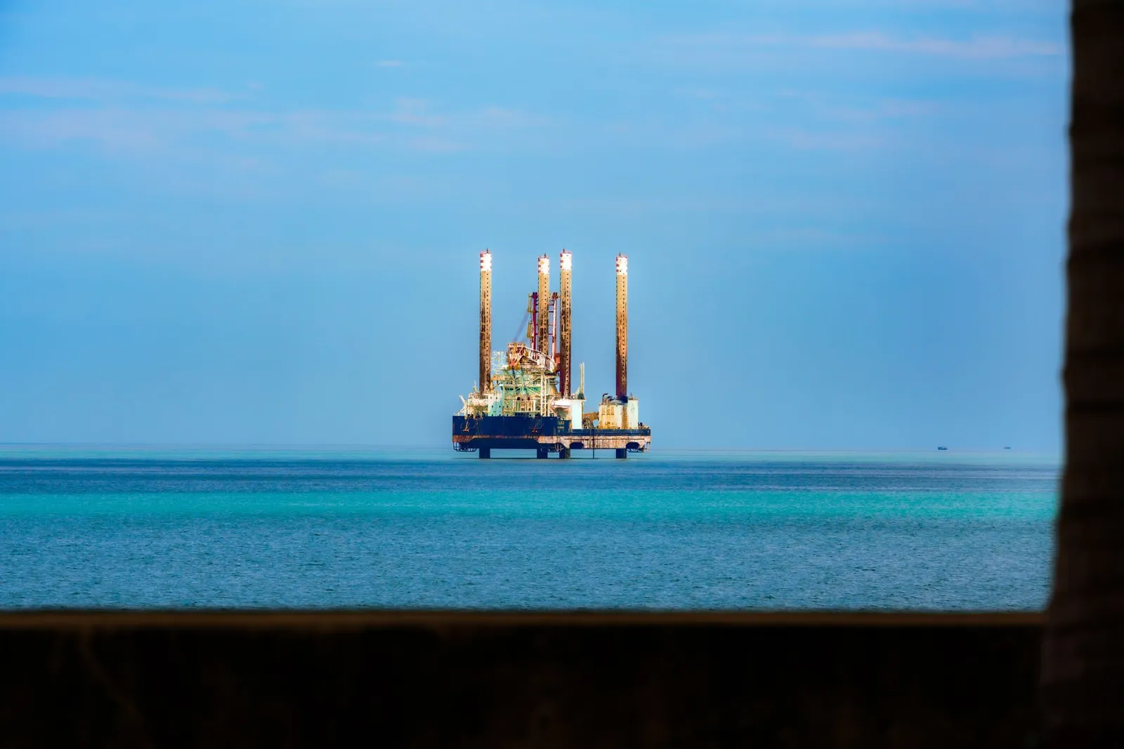 Distant view of an offshore oil rig in a calm, blue ocean under a clear sky. Stock photo illustrating Garden Reach Shipbuilders & Engineers' new order story.