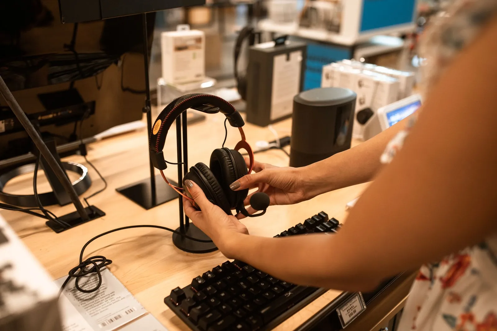 A woman examines headphones in an electronics store, focusing on the audio device's features. Stock photo illustrating Creative Newtech's product launched story.