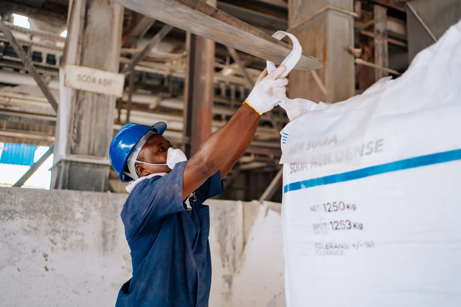 Industrial worker checking a large soda ash bag in a manufacturing facility. Stock photo illustrating Shivalik Rasayan's fund raise story.
