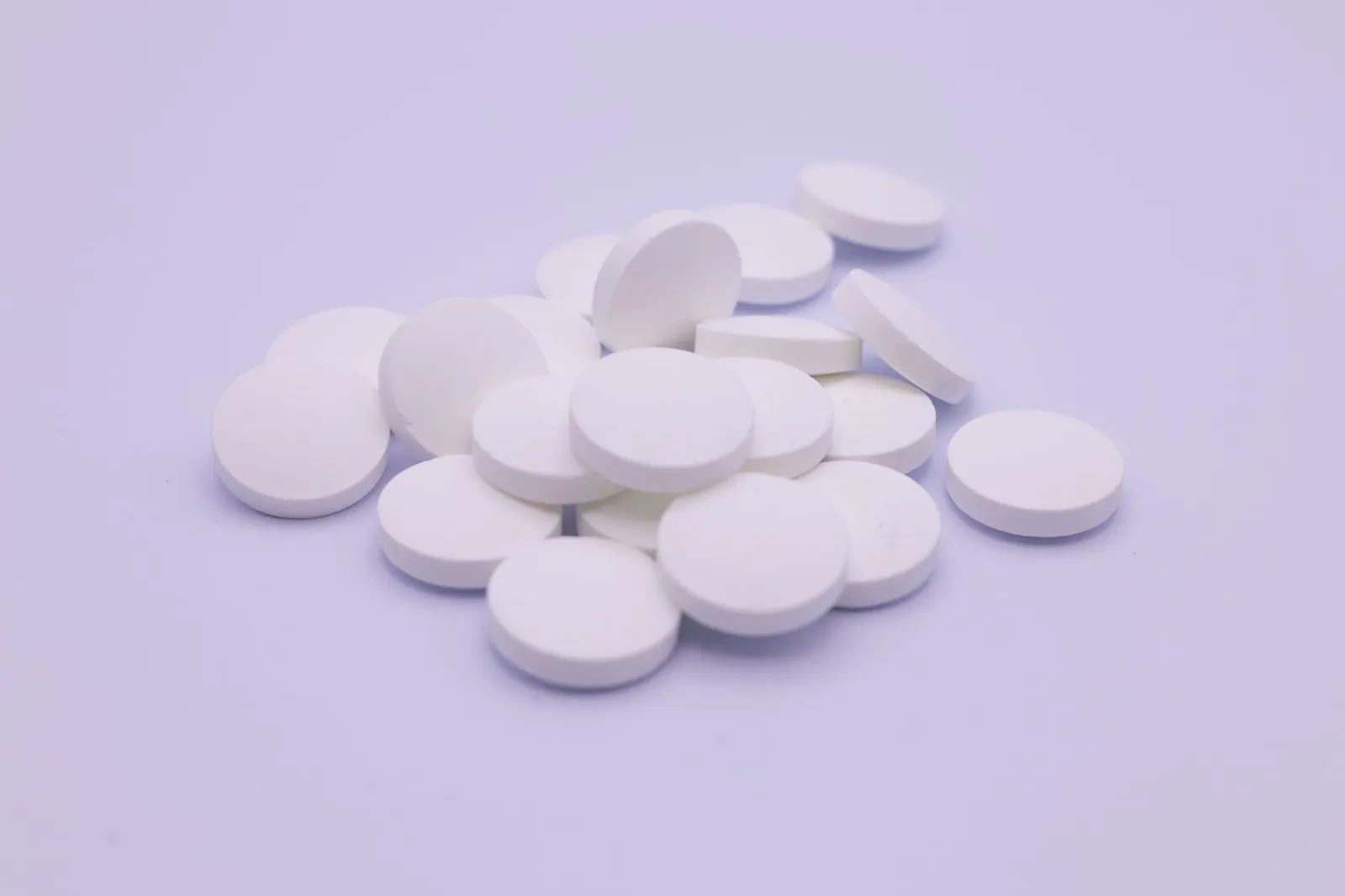 Assorted white tablets stacked on a soft purple surface, symbolizing medication and healthcare. Stock photo illustrating Kwality Pharmaceuticals' earning call story.
