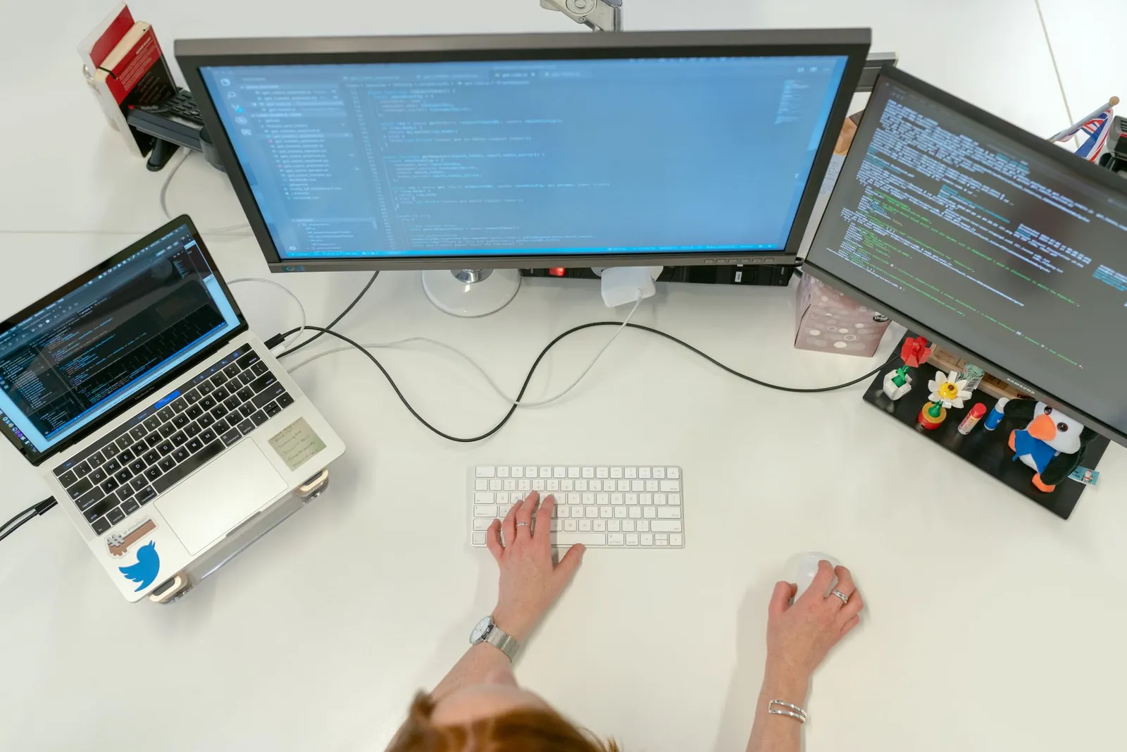 A female software engineer coding on dual monitors and a laptop in an office setting. Stock photo illustrating HCL Technologies' partnership story.