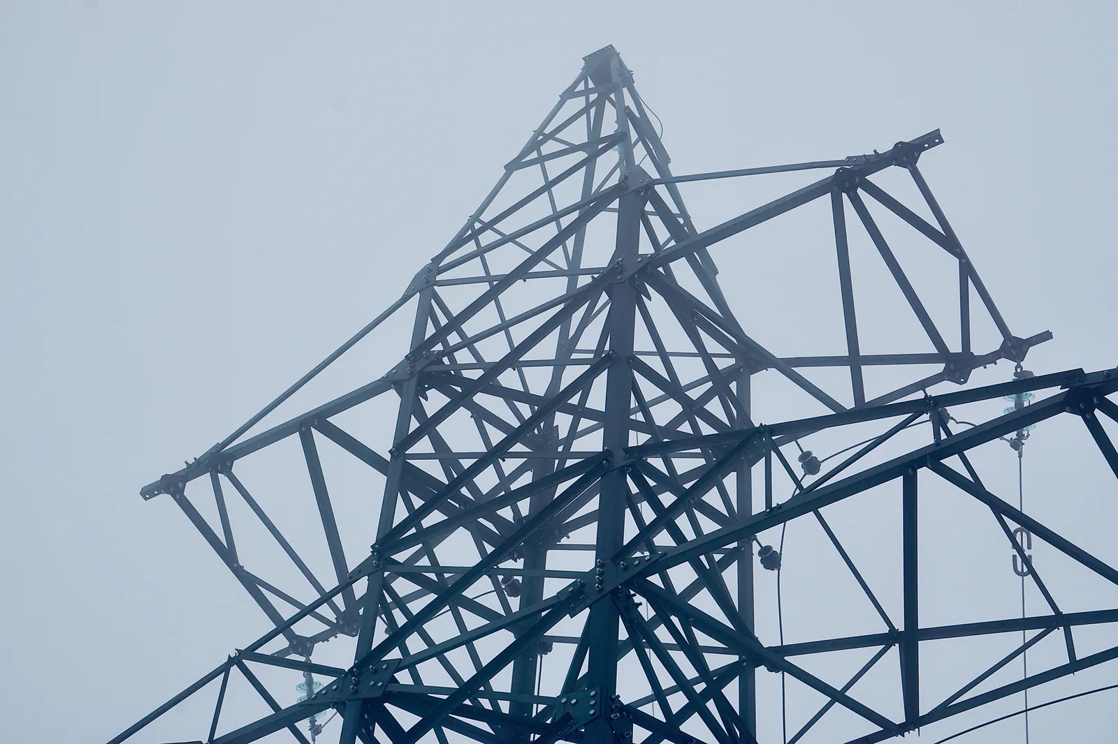 Close-up of a steel transmission tower against a foggy sky, emphasizing industrial design. Stock photo illustrating Bajel Projects' new order story.