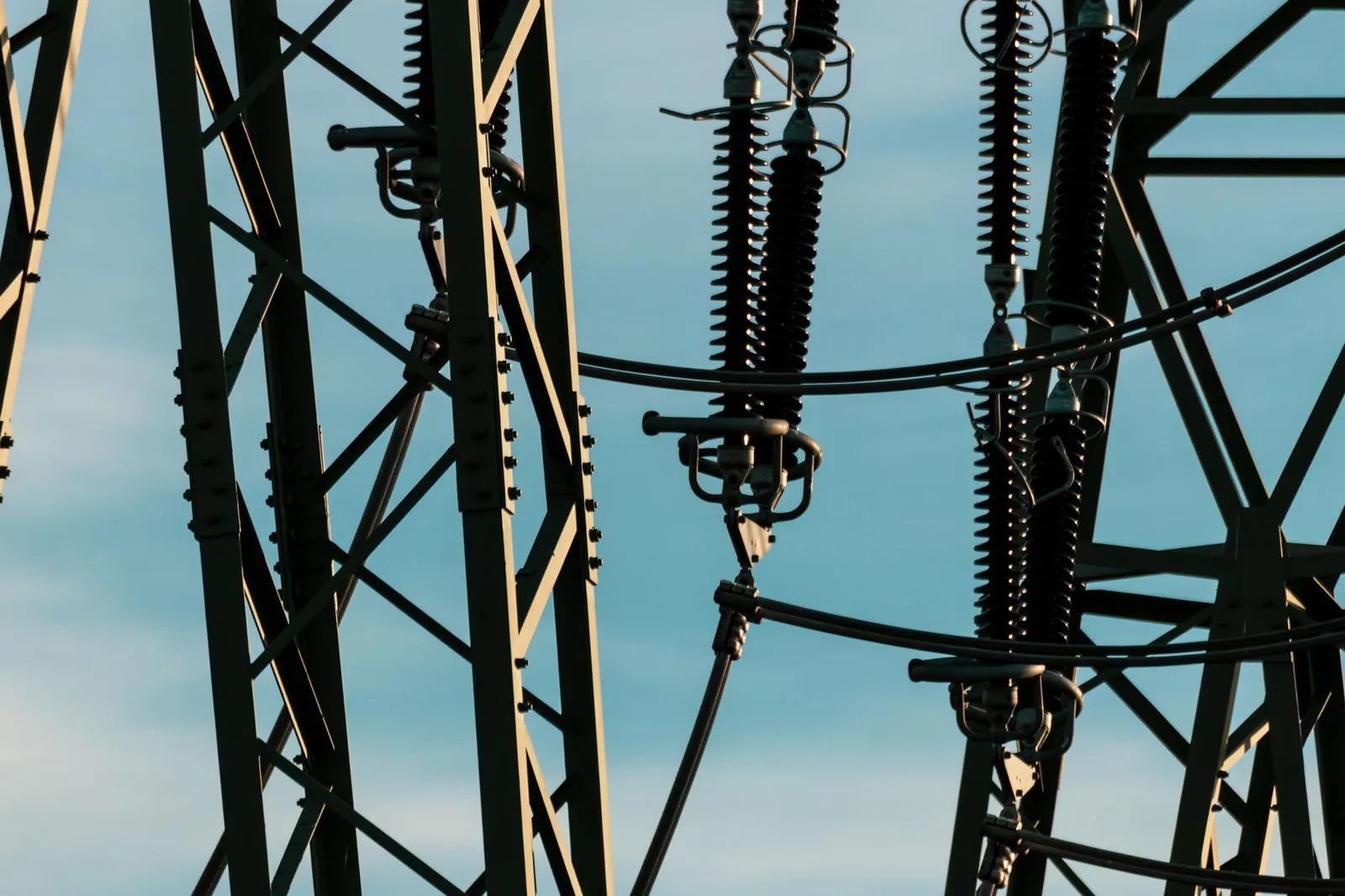 Detailed shot of power lines and electrical insulators set against a vivid blue sky. Stock photo illustrating Hind Rectifiers' fund raise story.