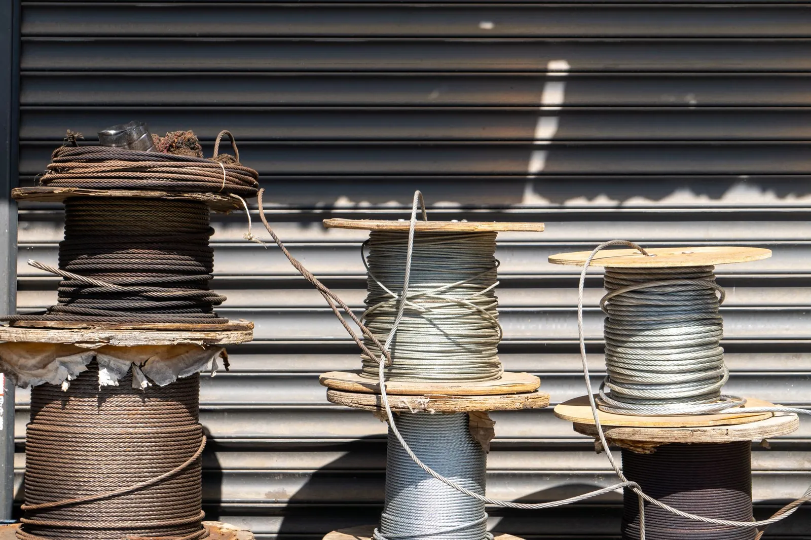 Multiple large spools of industrial cable placed outdoors in front of a closed shutter. Stock photo illustrating Cryogenic OGS's new order story.