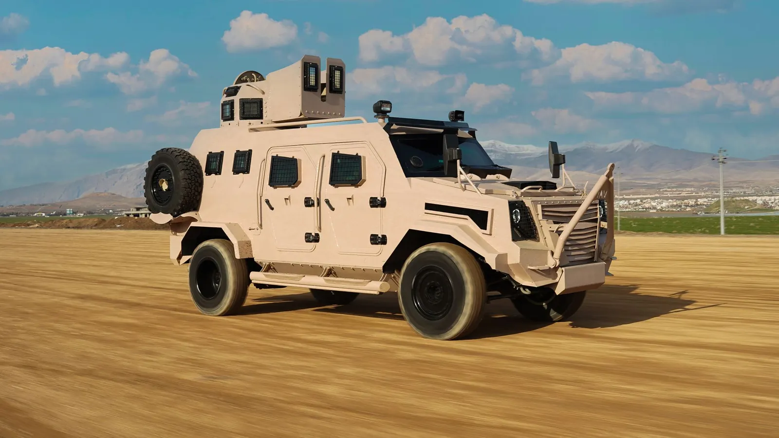 An armored military vehicle drives on a dirt road with mountain backdrop in Kurdistan. Stock photo illustrating Bharat Forge's product launched story.