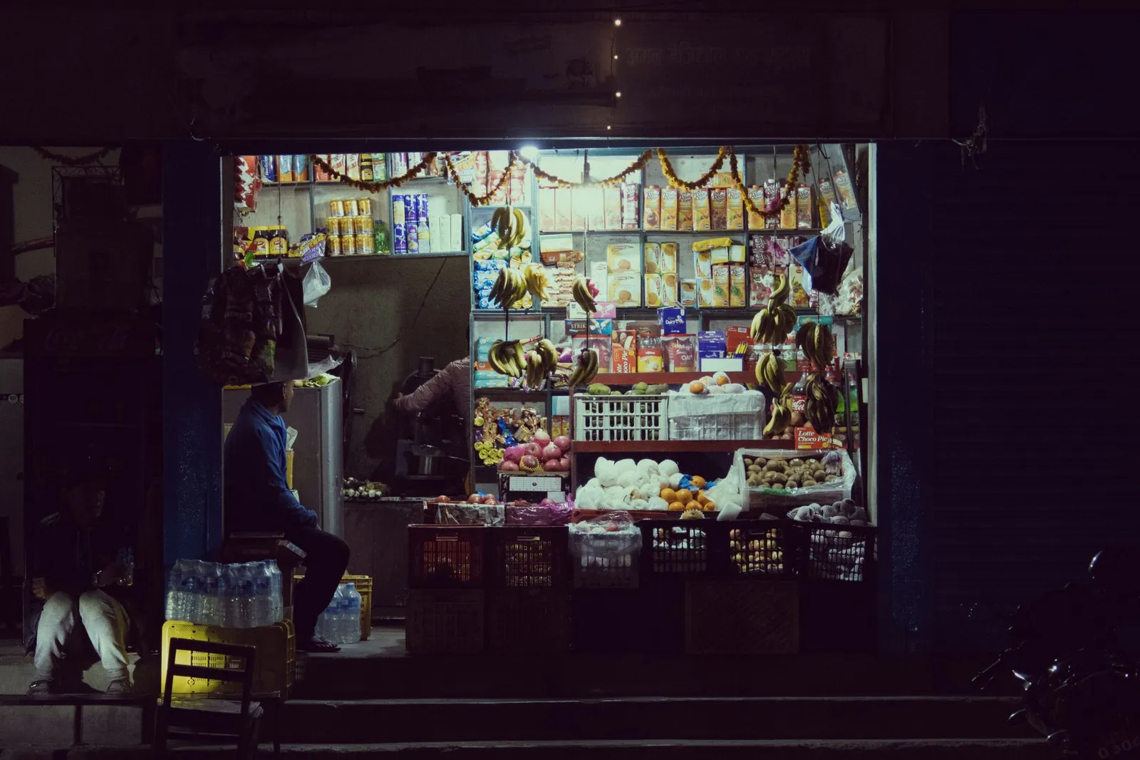 A small street vendor shop at night with illuminated merchandise and groceries. Stock photo illustrating Tata Teleservices (Maharashtra)'s product launched story.