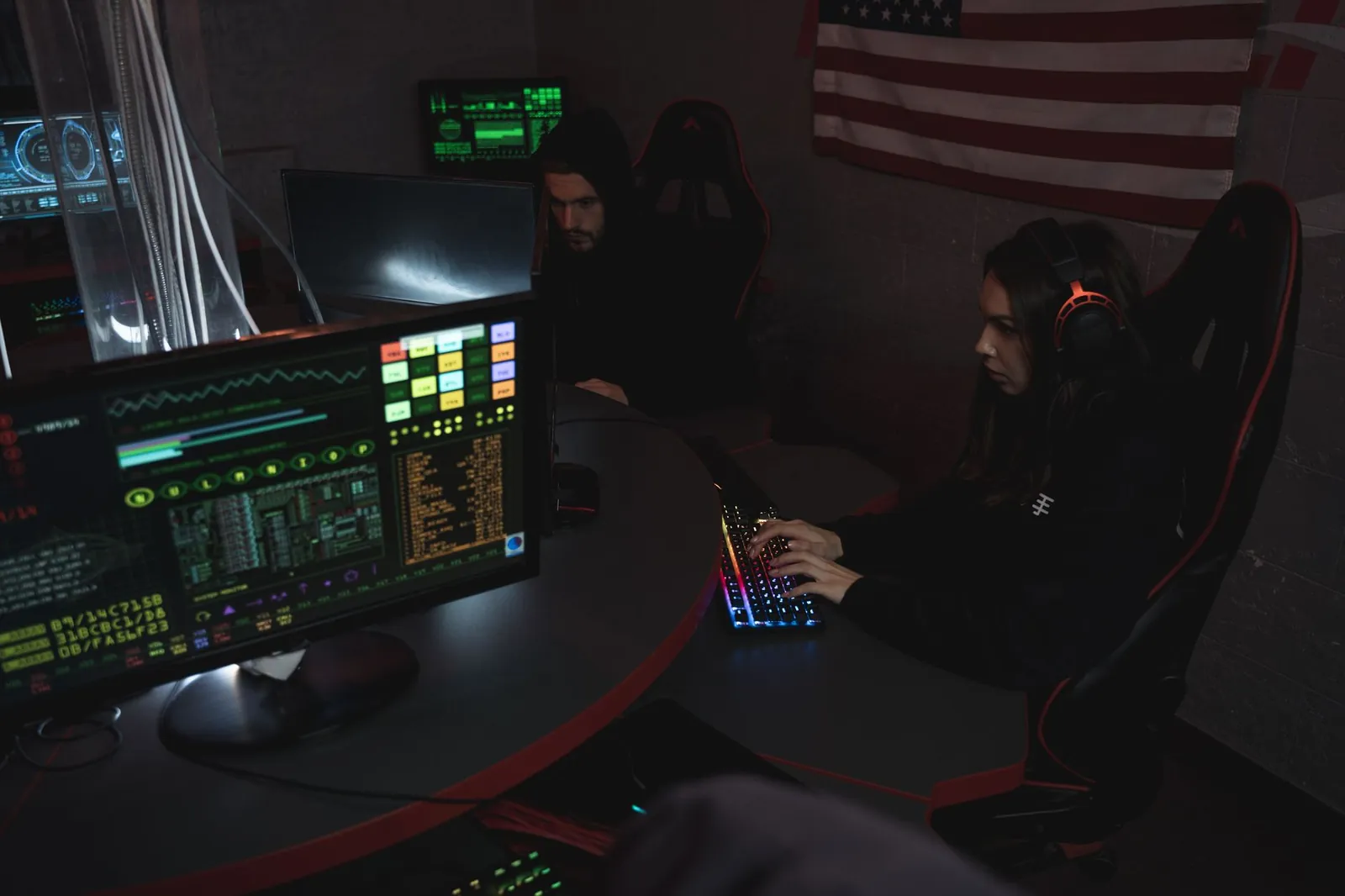 Cybersecurity professionals working on computer systems, focusing on data protection in a dimly lit room. Stock photo illustrating Orient Technologies' partnership story.