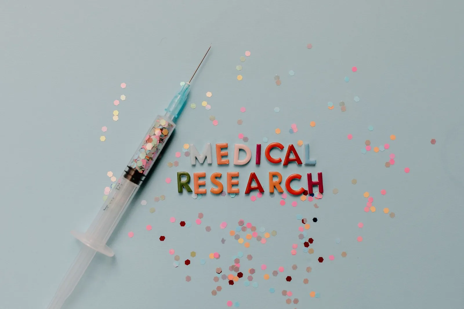 Close-up of a syringe with colorful confetti on medical research theme. Stock photo illustrating Granules India's product launched story.