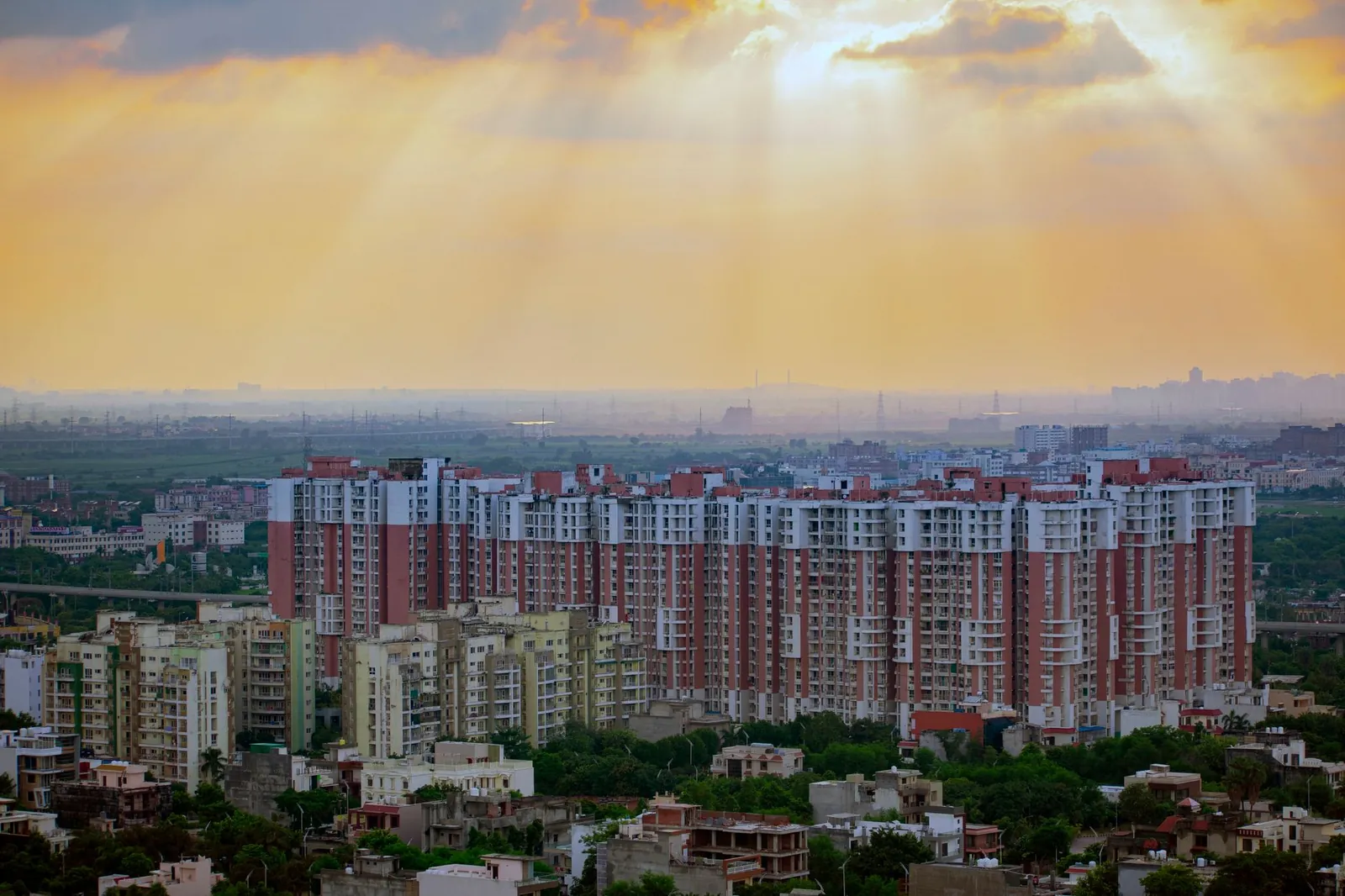 Captivating aerial view of Noida's residential skyline at sunrise, showcasing modern architecture and dramatic skies. Stock photo illustrating Embassy Developments' product launched story.