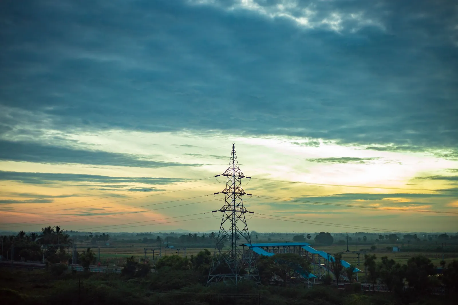 A stunning sunrise view over rural fields in Nanguneri, India with an electric tower. Stock photo illustrating India Power Corporation's financial results story.