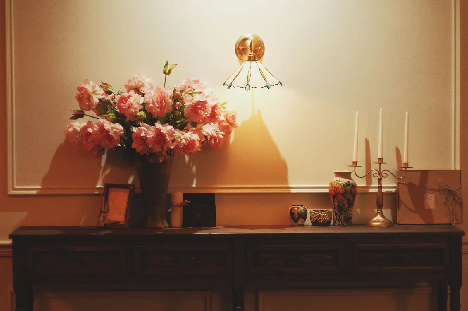 Warm vintage interior with pink flowers, vase, and candle holders on a wooden table. Stock photo illustrating Crompton Greaves Consumer Electricals' product launched story.