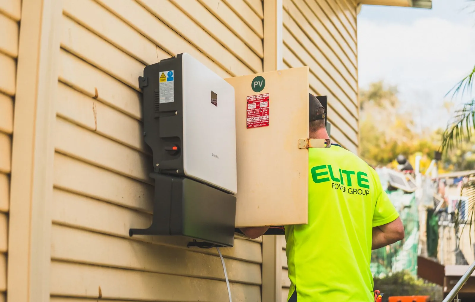 Electrician from Elite Power Group installing a solar inverter outside. Stock photo illustrating Servotech Renewable Power System's product launched story.