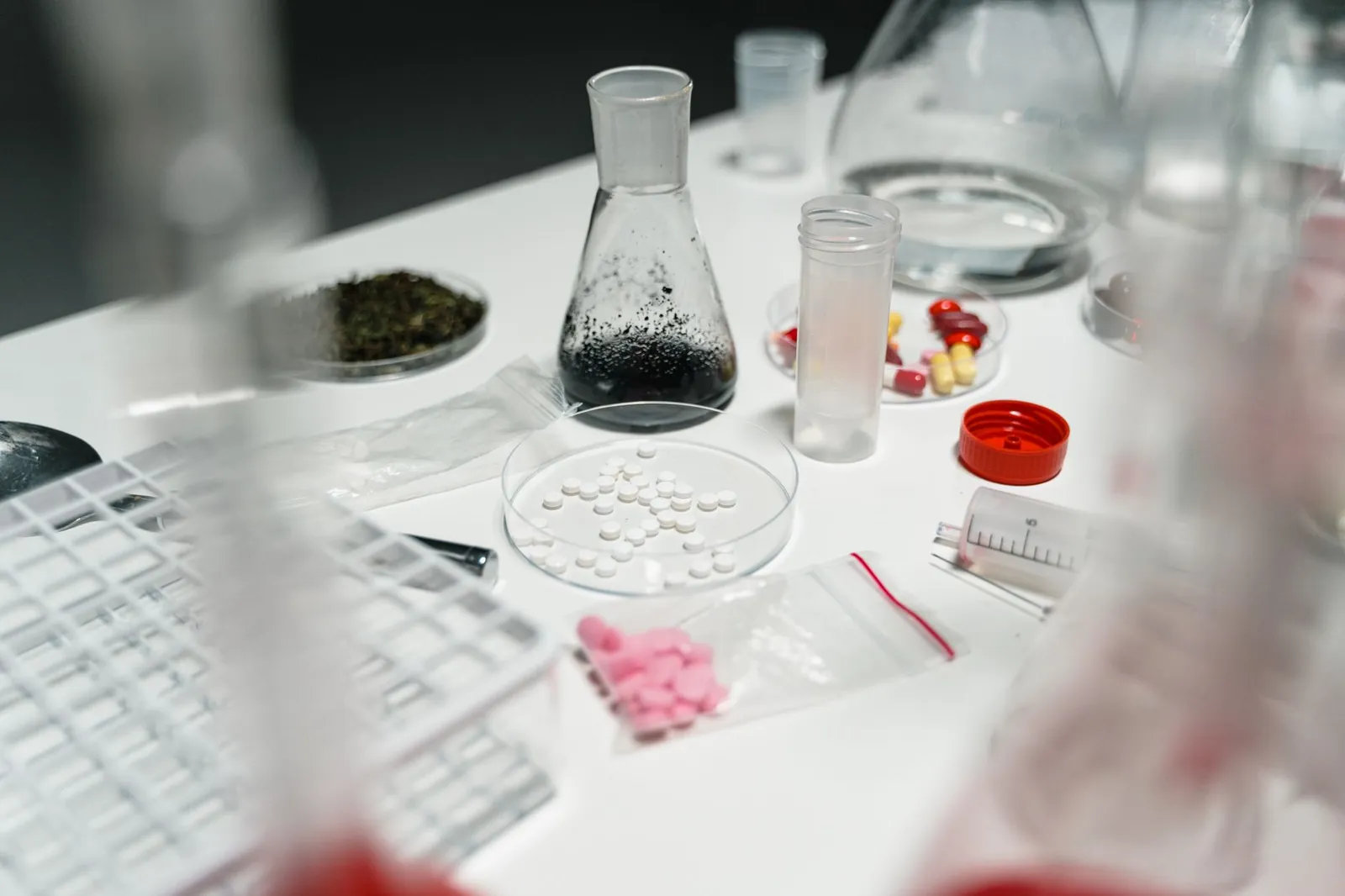A laboratory table displaying pills, petri dishes, and chemical beakers for scientific research. Stock photo illustrating Alembic Pharmaceuticals' earning call story.