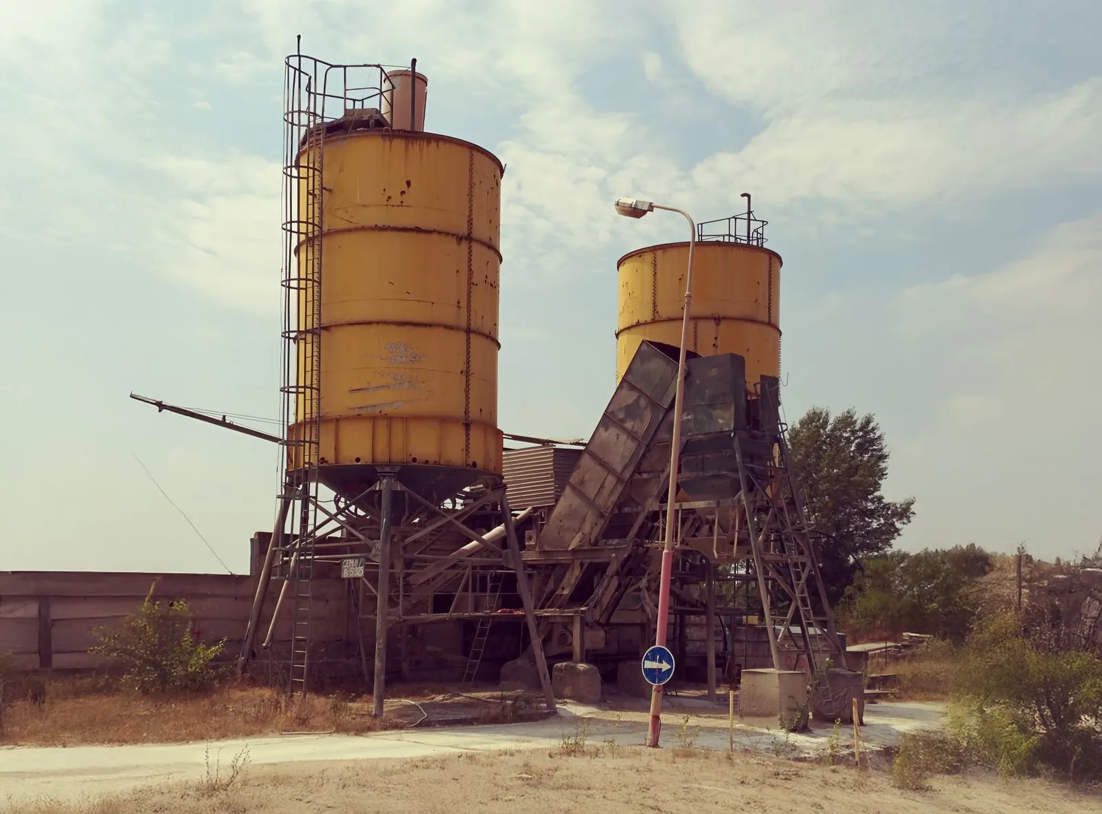 Abandoned yellow silos in a desolate industrial area with a dystopian feel. Stock photo illustrating Grasim Industries' promoter buying story.