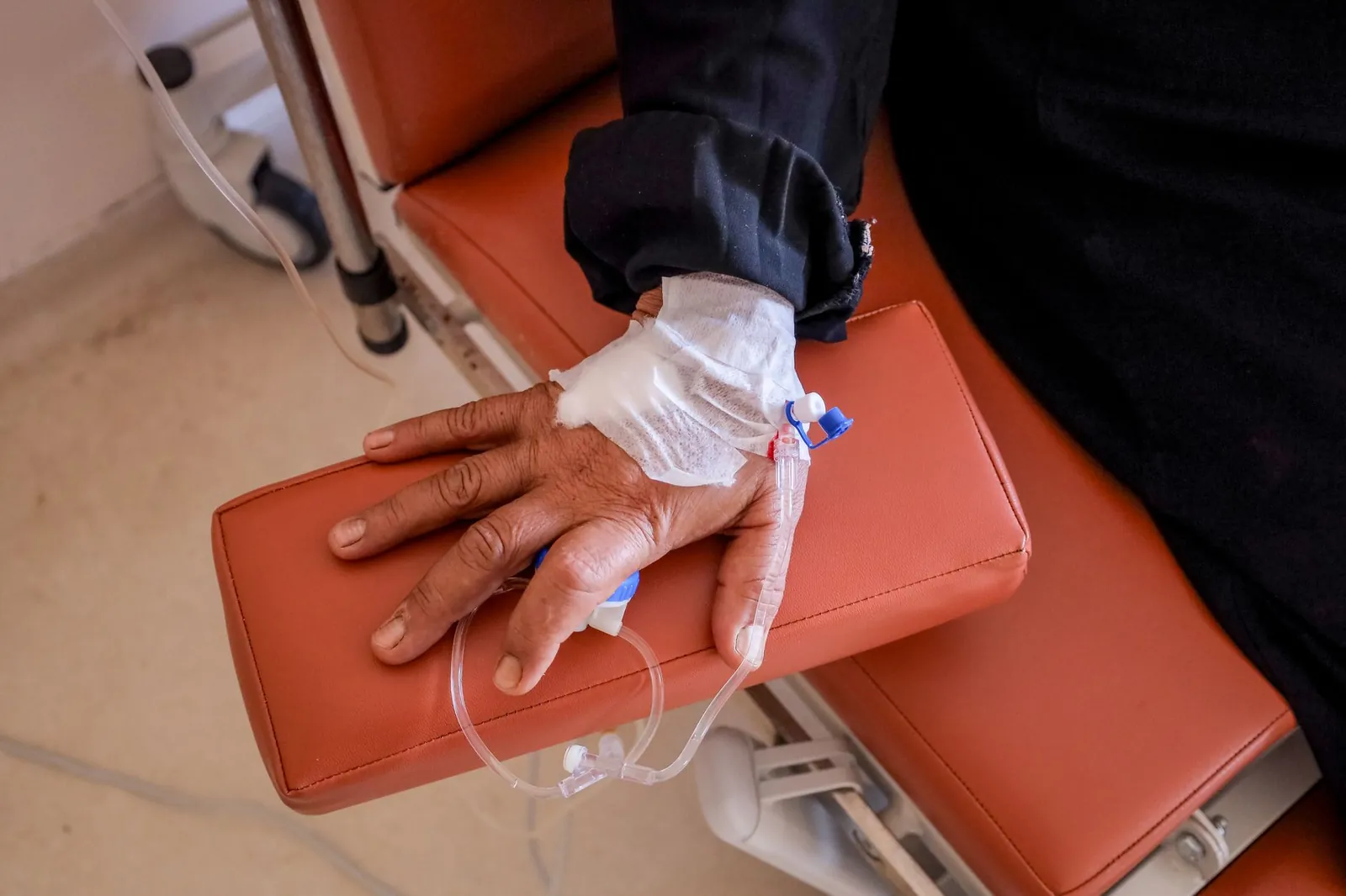 Close-up of a patient's hand receiving chemotherapy treatment in a medical facility. Stock photo illustrating Sakar Healthcare's earning call story.