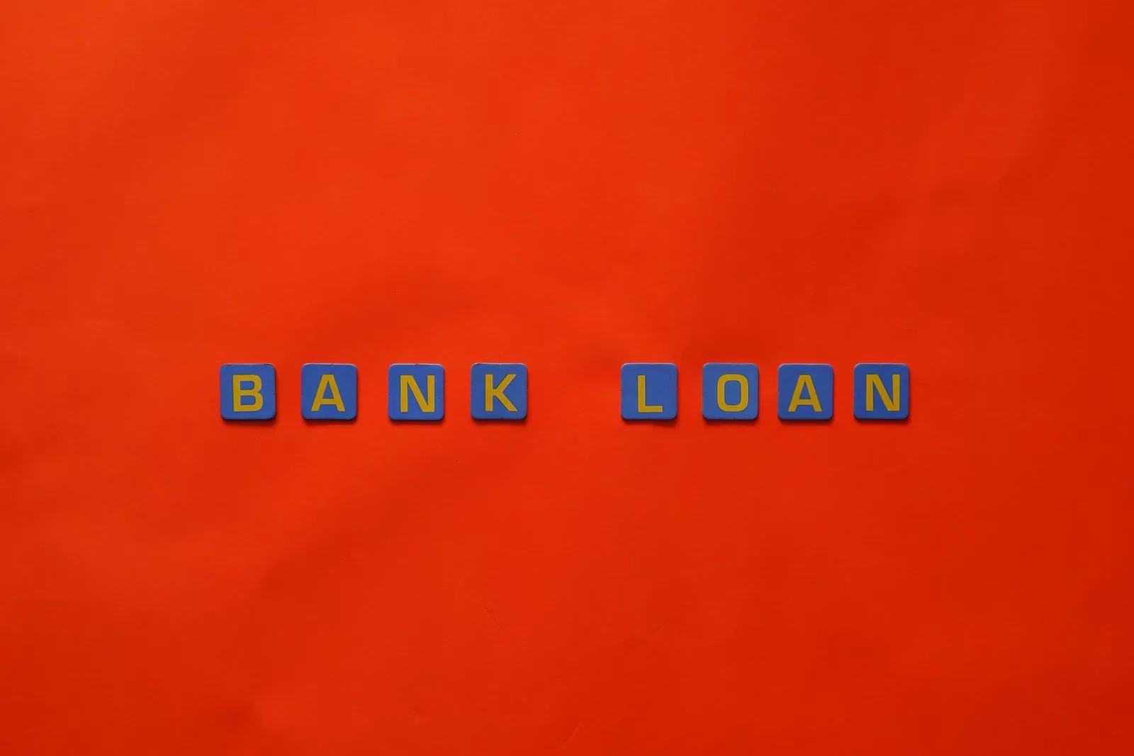Letters forming 'Bank Loan' on a vibrant red surface, ideal for finance themes. Stock photo illustrating Suryoday Small Finance Bank's fund raise story.