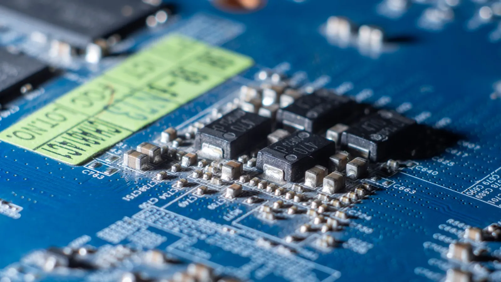 Detailed macro shot of a blue circuit board with multiple microchips and electronic components. Stock photo illustrating Apollo Micro Systems' new order story.