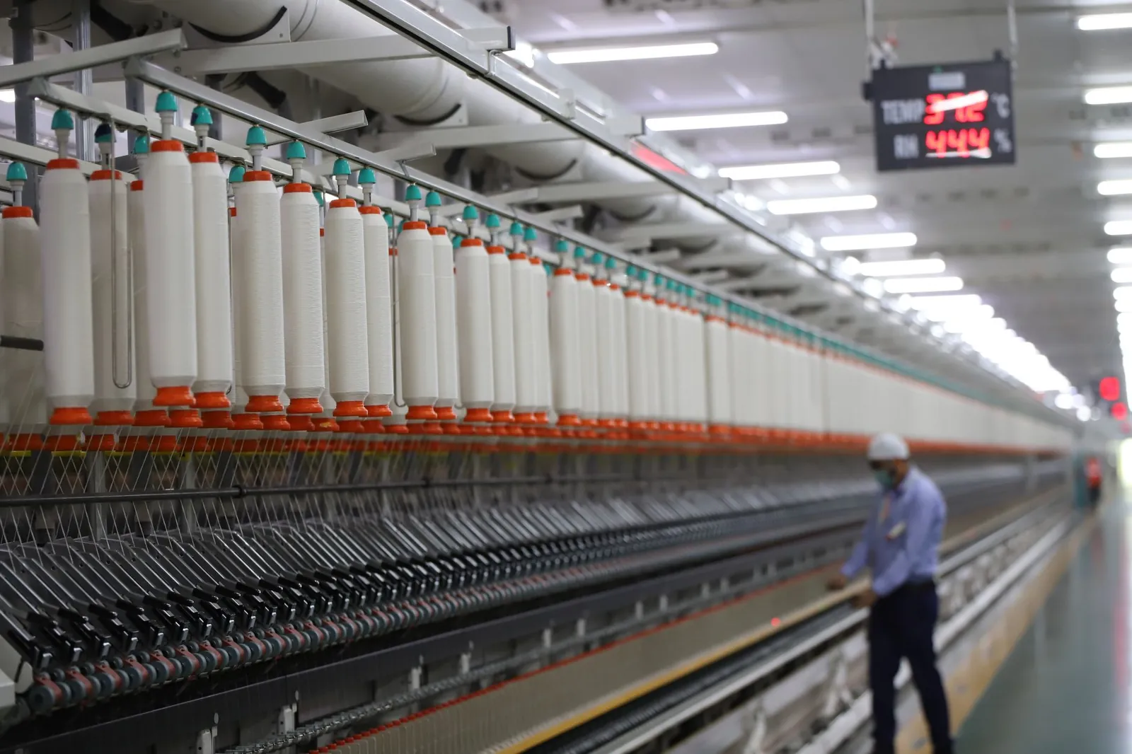 A worker manages textile machinery in a modern industrial plant in India. Stock photo illustrating Sumeet Industries' fund raise story.