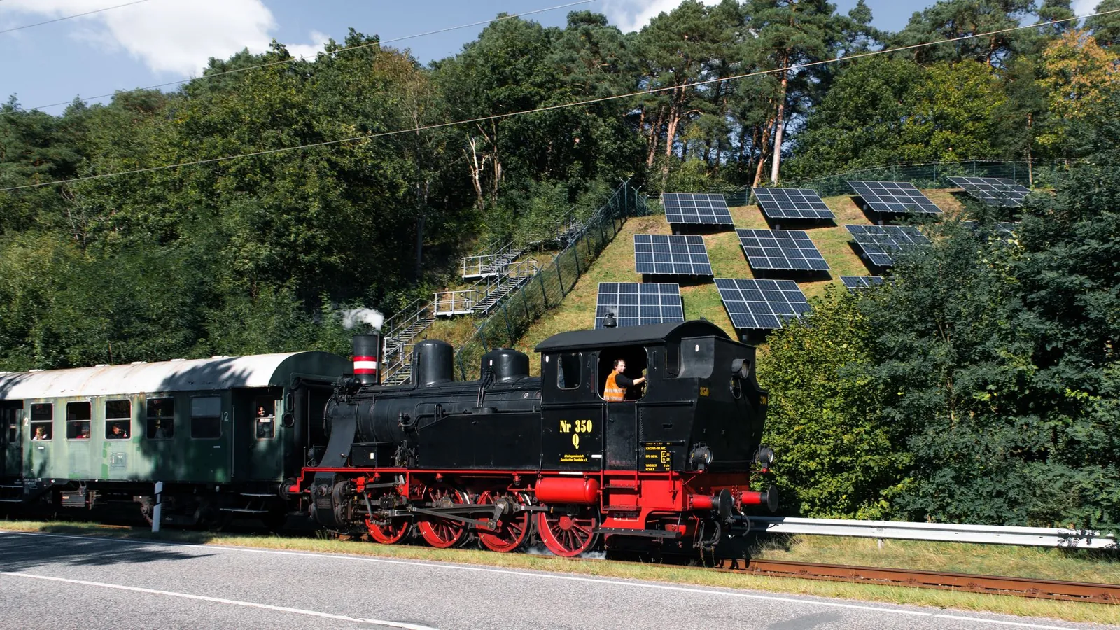 Historical steam locomotive beside modern solar panels, blending nostalgia with technology. Stock photo illustrating ACME Solar Holdings' new order story.