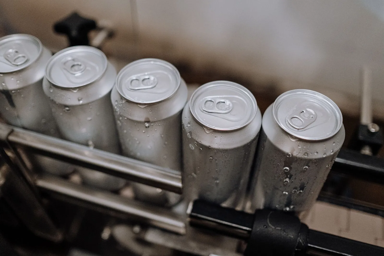 Detail view of aluminum cans with condensation in a manufacturing setting. Stock photo illustrating GSM Foils' expansion story.