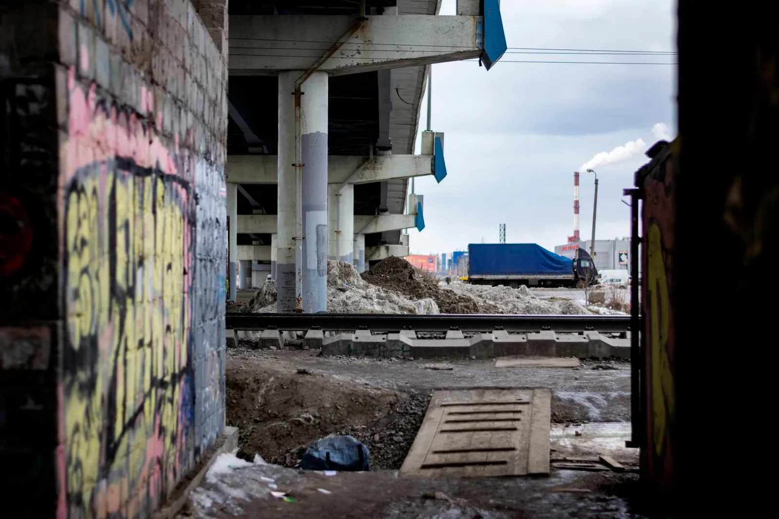 Concrete pillars and graffiti under a highway bridge in an urban construction site. Stock photo illustrating GPT Infraprojects' earning call story.