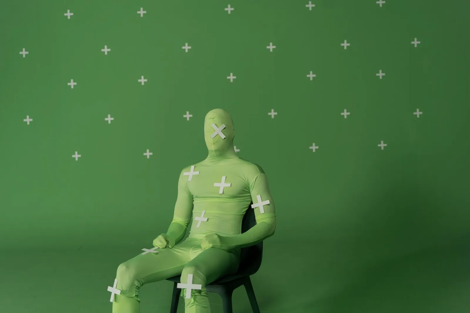 Person in chroma key suit sitting in green screen studio for visual effects creation. Stock photo illustrating Basilic Fly Studio's new order story.