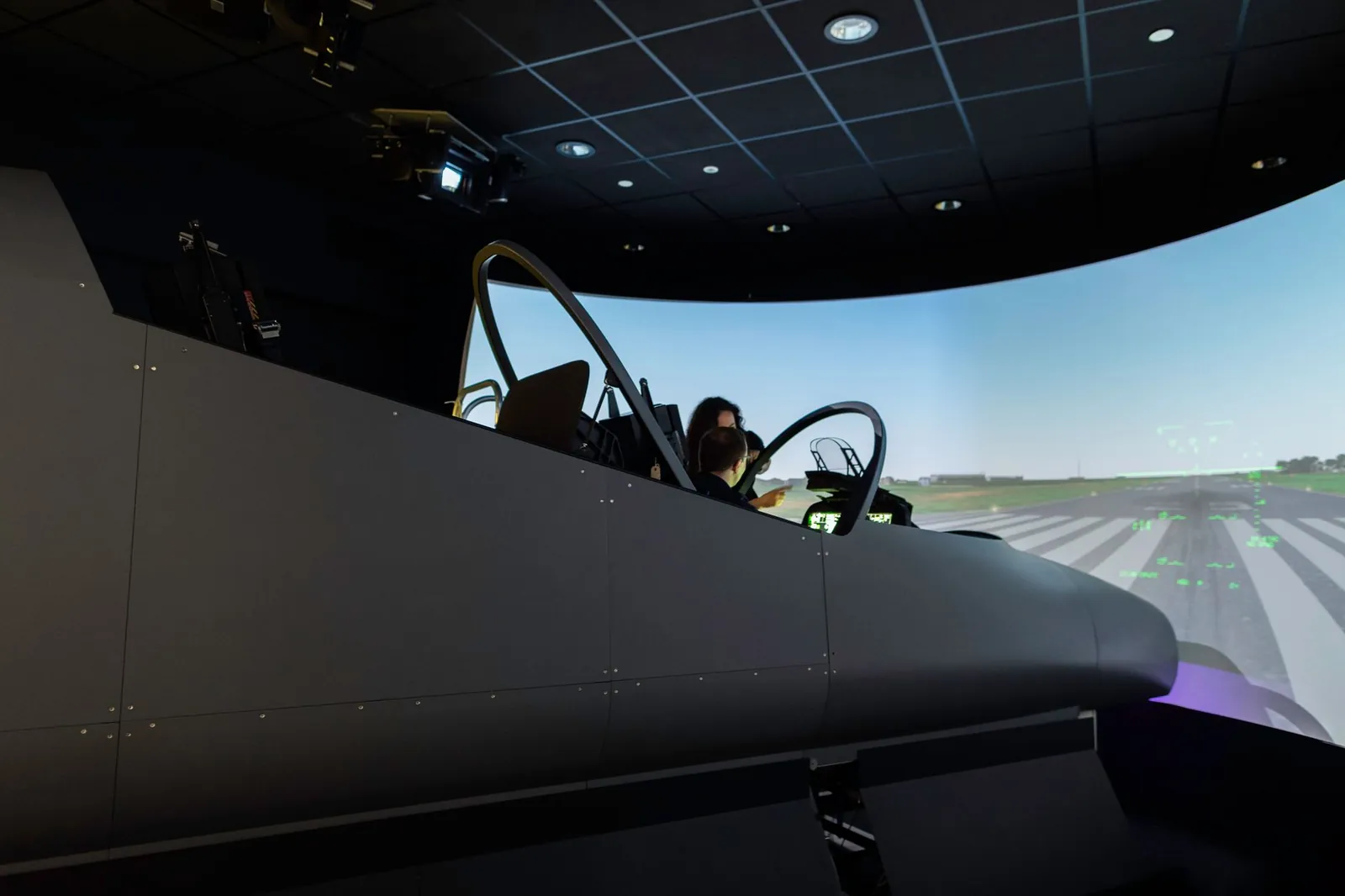A female pilot operates a flight simulator in an advanced training facility. Stock photo illustrating C.E. Info Systems' partnership story.