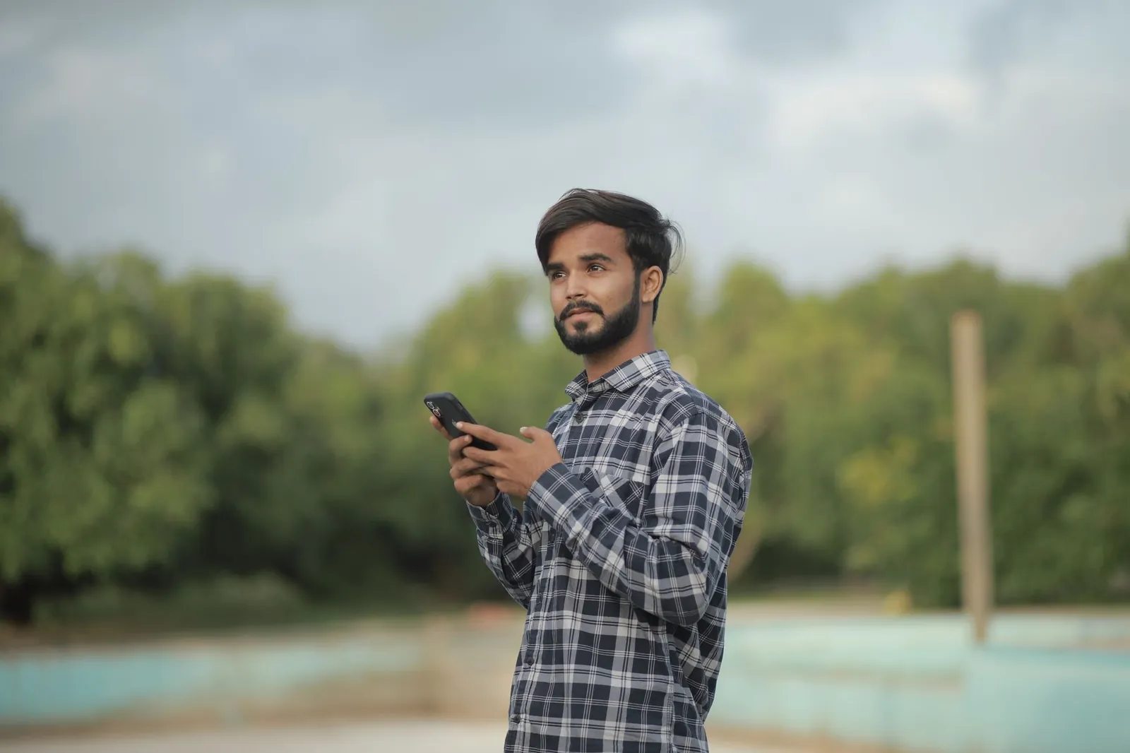 Portrait of a man using a smartphone outdoors in a casual environment. Stock photo illustrating Avio Smart Market Stack's partnership story.