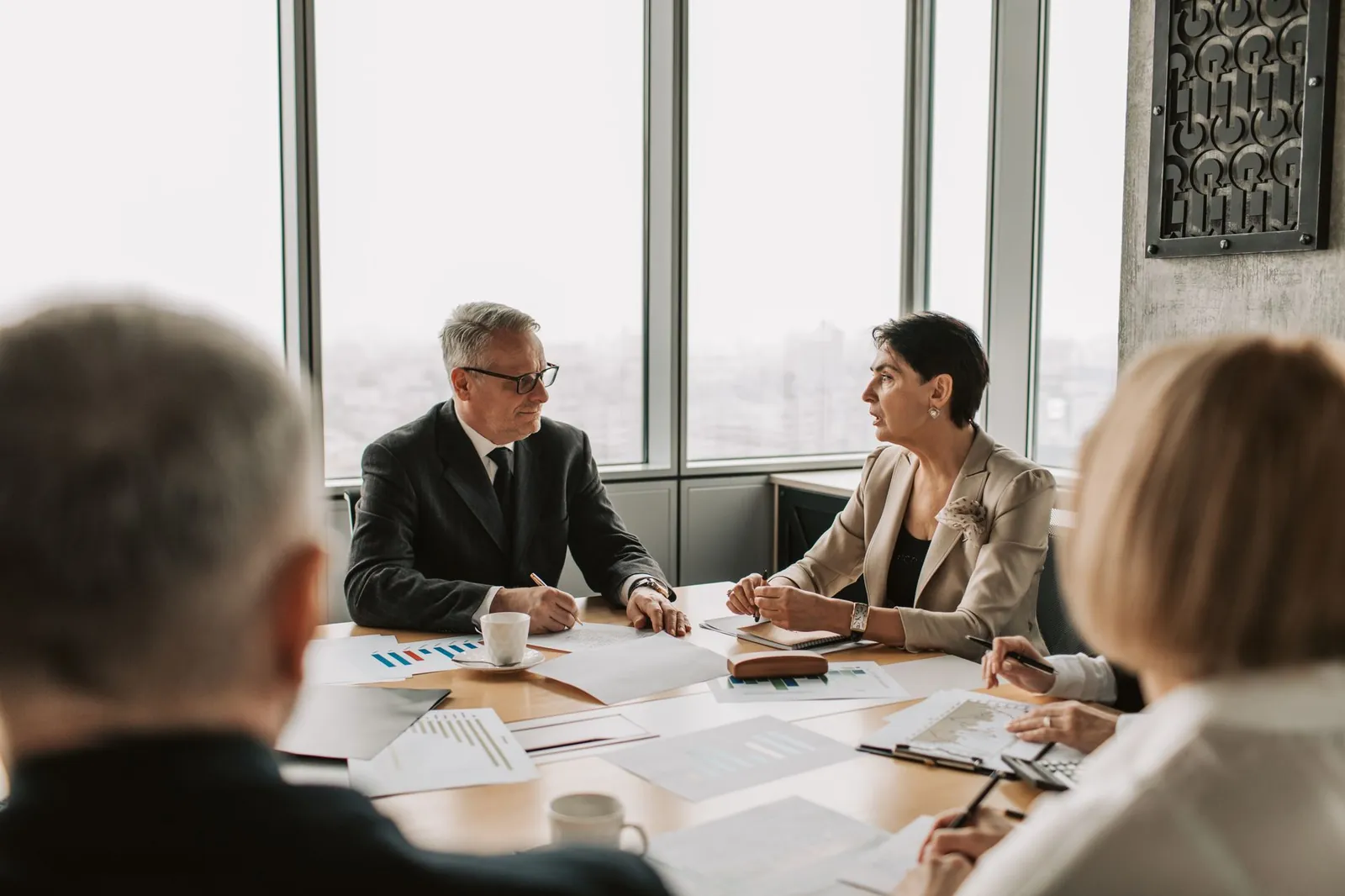 Business professionals engaged in a strategic meeting in a modern office setting with natural light. Stock photo illustrating Charms Industries' regulatory approval story.