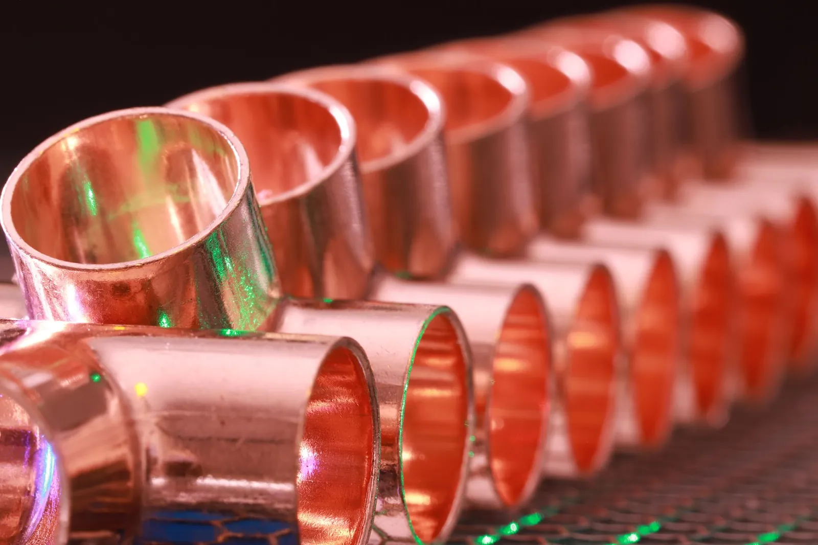 Copper plumbing fittings arranged in a row, showcasing metallic texture and industrial detail. Stock photo illustrating KSH International's production started story.