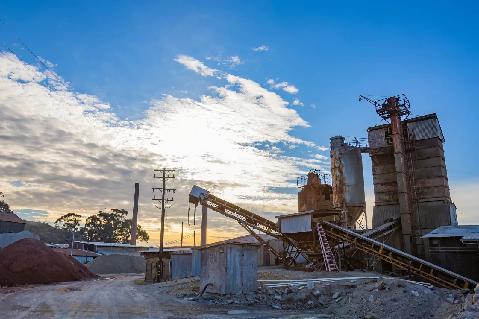 A factory with rusty structures set against a stunning sunrise in an industrial landscape. Stock photo illustrating Bharat Coking Coal's production started story.
