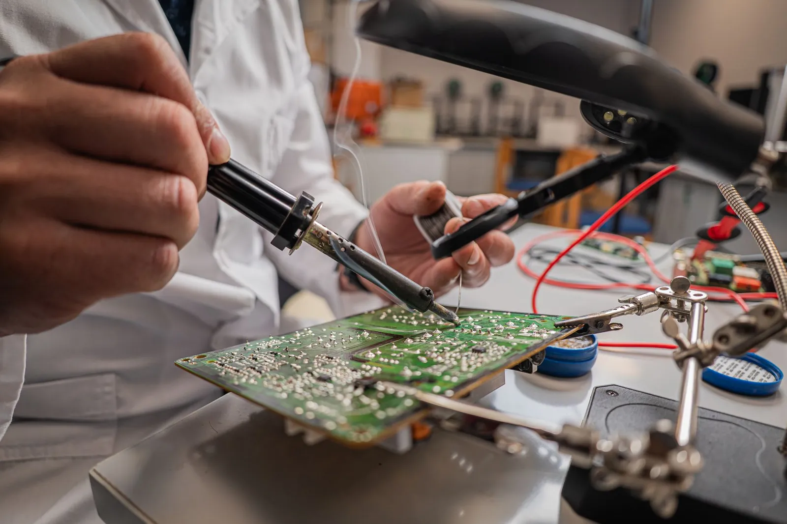 A skilled technician soldering electronic components on a green circuit board in a laboratory. Stock photo illustrating Artificial Electronics Intelligent Material's fund raise story.