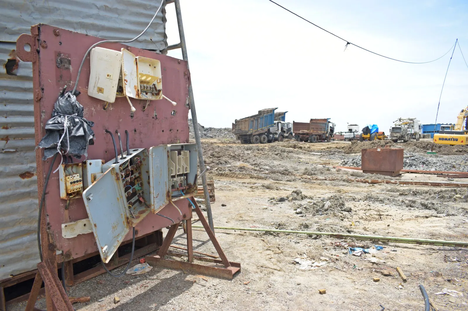 A barren construction site with rusted electrical panel and heavy equipment in the background. Stock photo illustrating Current Infraprojects' new order story.