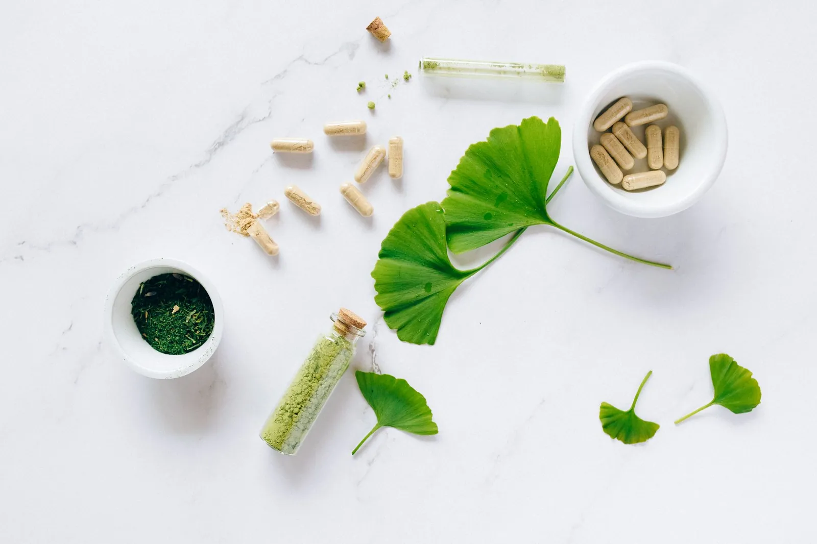 Flat lay of herbal supplements with ginkgo leaves on marble surface, emphasizing natural health remedies. Stock photo illustrating Jeena Sikho Lifecare's product launched story.